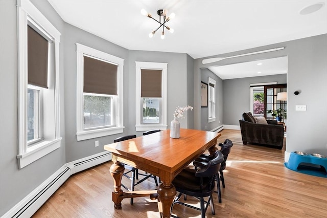 dining space featuring a chandelier, light wood-style flooring, and a baseboard radiator