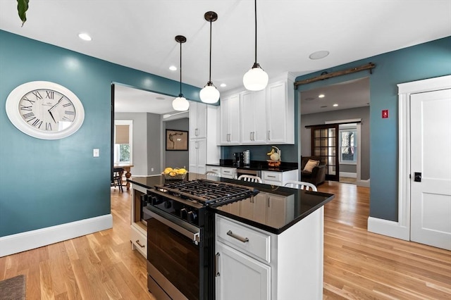 kitchen featuring gas range oven, dark countertops, a healthy amount of sunlight, and light wood-style flooring