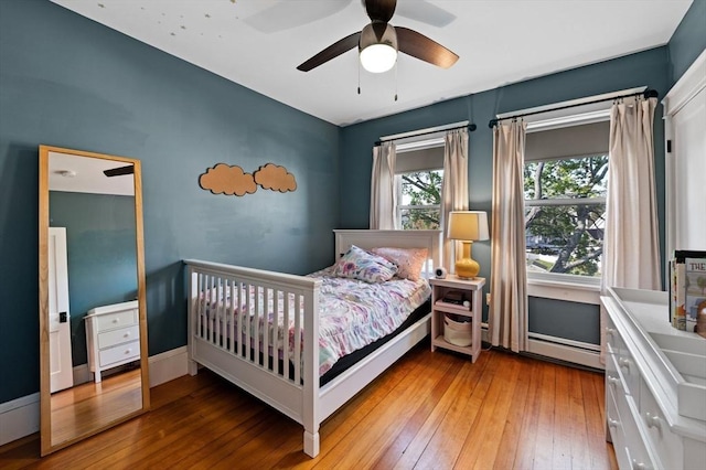 bedroom with ceiling fan, baseboards, baseboard heating, and hardwood / wood-style floors