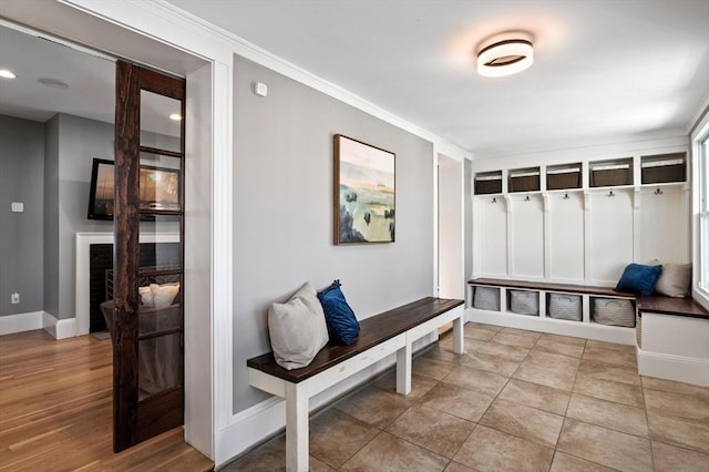 mudroom with baseboards, ornamental molding, and a fireplace