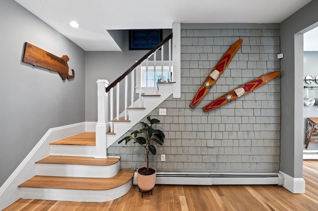 staircase with a baseboard heating unit, baseboards, recessed lighting, and wood finished floors