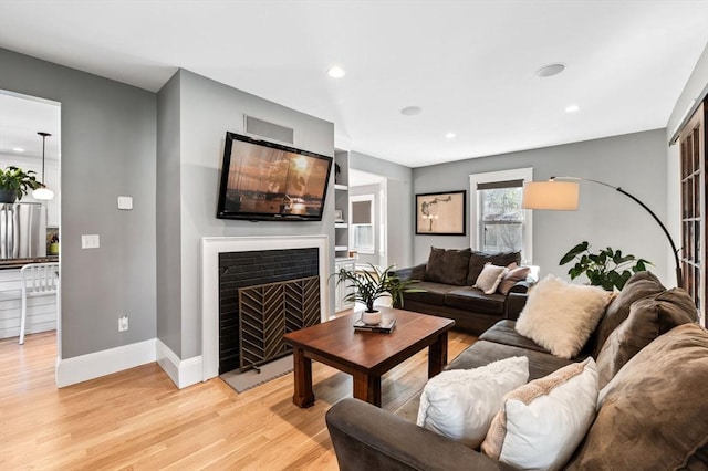 living area with light wood-style floors, baseboards, a fireplace, and recessed lighting