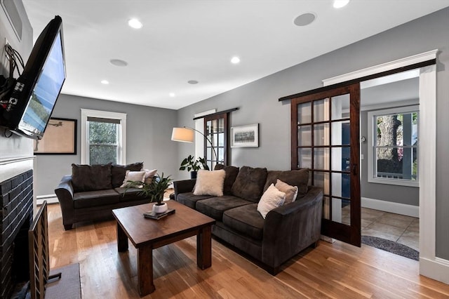 living room featuring baseboards, wood finished floors, a fireplace, and recessed lighting