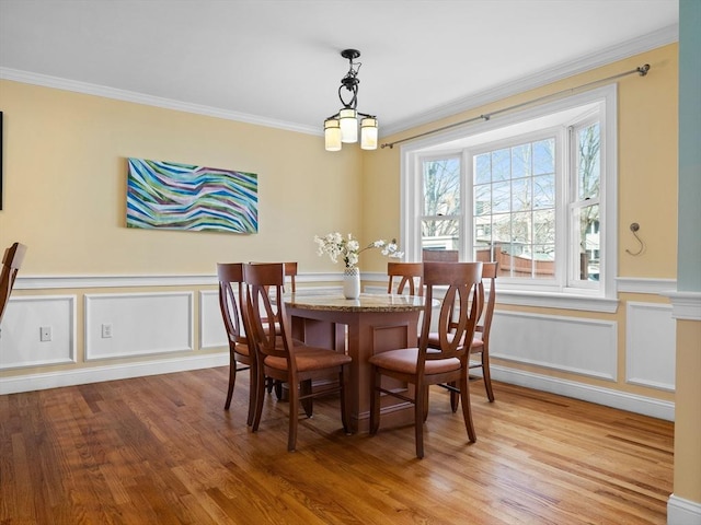 dining space with a wainscoted wall, light wood-type flooring, and ornamental molding