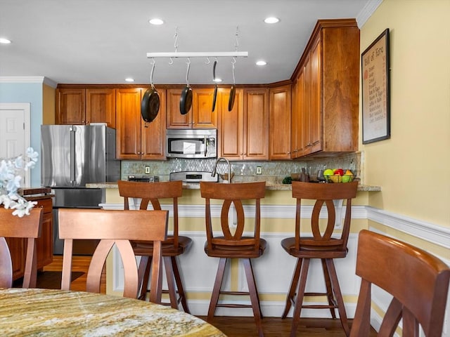 kitchen featuring decorative backsplash, a kitchen breakfast bar, brown cabinets, and appliances with stainless steel finishes