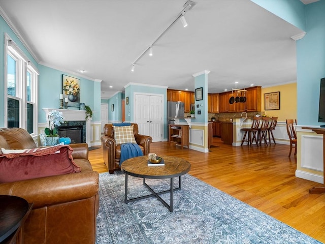 living area featuring recessed lighting, a fireplace, crown molding, and light wood-style floors