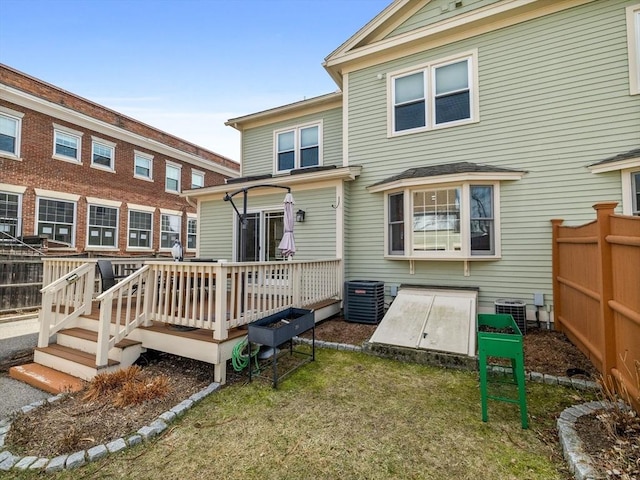 rear view of house featuring a deck, central air condition unit, a yard, and fence