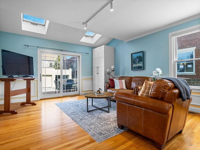 living area with rail lighting, a skylight, crown molding, and light wood-style floors