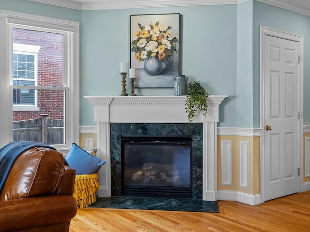 sitting room featuring crown molding, wood finished floors, baseboards, and a high end fireplace