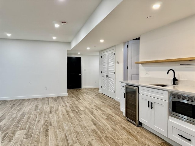 252 Main St Unit 101, Medford, MA 02155 - kitchen with wine cooler, stainless steel microwave, light wood-style flooring, white cabinets, and recessed lighting
