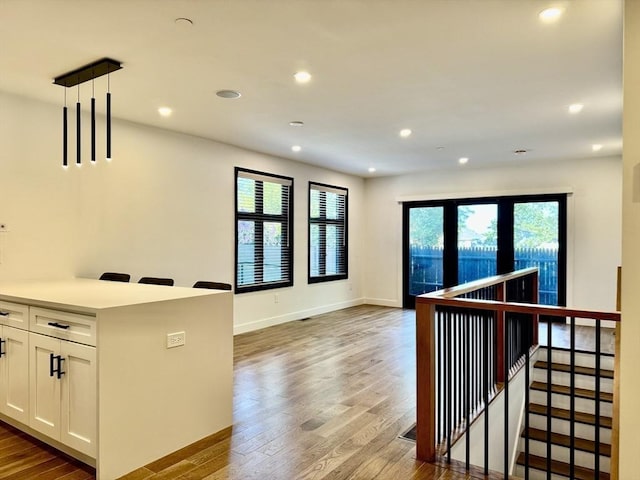 252 Main St Unit 101, Medford, MA 02155 - kitchen with wood finished floors, open floor plan, white cabinetry, recessed lighting, and decorative light fixtures