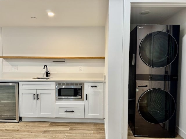252 Main St Unit 101, Medford, MA 02155 - laundry room featuring beverage cooler, stacked washer and clothes dryer, bar with sink, and light wood-style floors