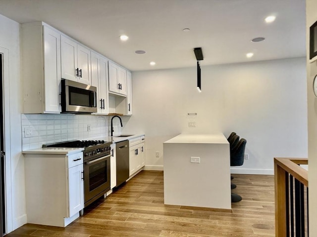 252 Main St Unit 101, Medford, MA 02155 - kitchen with appliances with stainless steel finishes, a sink, light wood-style flooring, tasteful backsplash, and recessed lighting