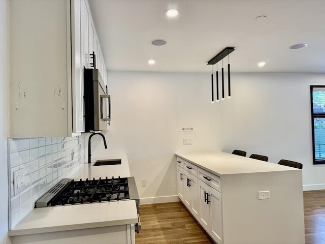 252 Main St Unit 101, Medford, MA 02155 - kitchen featuring stainless steel microwave, a sink, a peninsula, backsplash, and baseboards