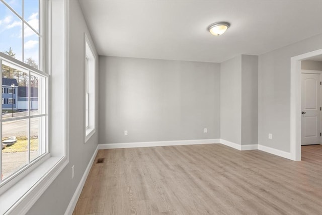 empty room featuring visible vents, baseboards, and light wood-style floors