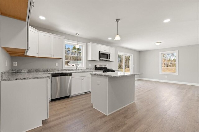 kitchen featuring a healthy amount of sunlight, white cabinetry, stainless steel appliances, and light wood-style floors