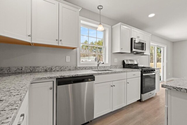 kitchen with white cabinetry, light wood-style flooring, appliances with stainless steel finishes, and a sink