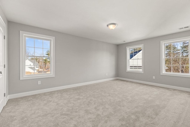 empty room with visible vents, baseboards, and light colored carpet
