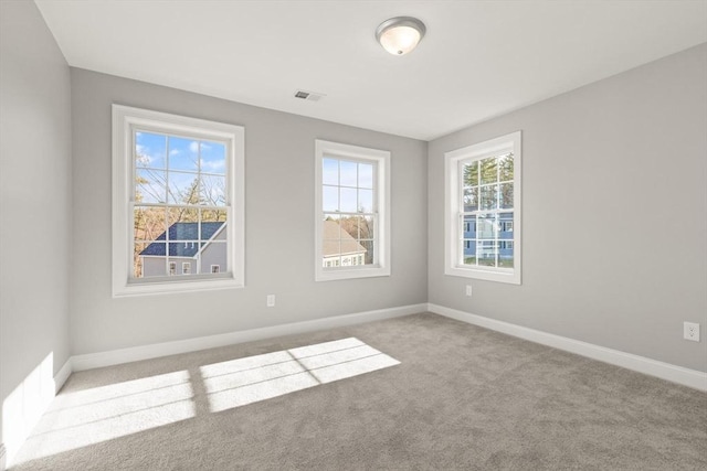 carpeted empty room featuring baseboards and visible vents