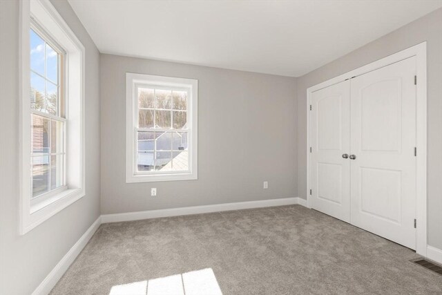 unfurnished bedroom with a closet, visible vents, carpet flooring, and baseboards