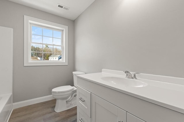 bathroom featuring vanity, wood finished floors, visible vents, baseboards, and toilet