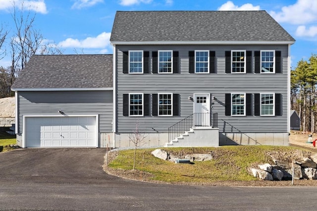 colonial home with driveway and a shingled roof