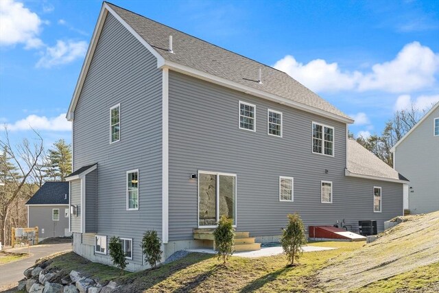 rear view of property featuring central air condition unit and roof with shingles