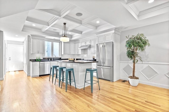 49 Baldwin St Unit 1, Boston, MA 02129 - kitchen with appliances with stainless steel finishes, dark countertops, light wood-style floors, decorative backsplash, and coffered ceiling