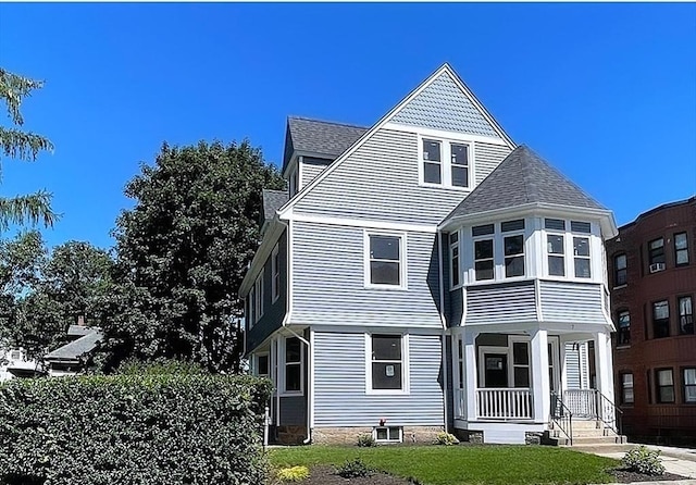 view of front of property with a shingled roof and a front yard