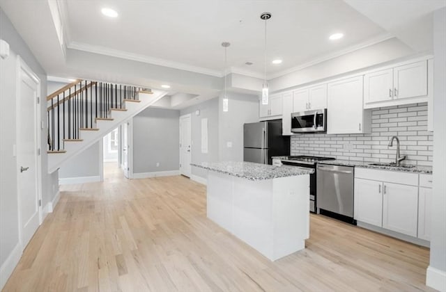 kitchen featuring a sink, white cabinetry, appliances with stainless steel finishes, a center island, and decorative light fixtures