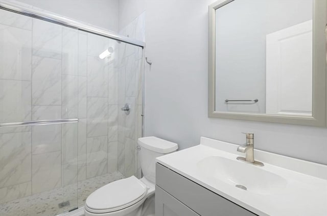 bathroom featuring vanity, a shower stall, and toilet