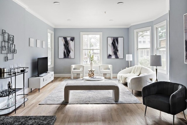 living area with baseboards, crown molding, and light wood finished floors