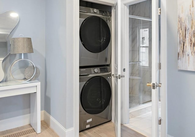 clothes washing area featuring stacked washer and dryer, laundry area, and baseboards