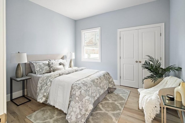 bedroom featuring a closet, light wood-type flooring, and baseboards