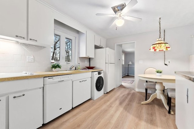 kitchen with white appliances, light hardwood / wood-style floors, white cabinets, washer / clothes dryer, and decorative light fixtures