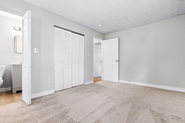 unfurnished bedroom with ensuite bath, light colored carpet, and a closet