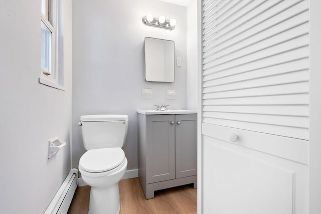 bathroom with vanity, hardwood / wood-style floors, a baseboard radiator, and toilet