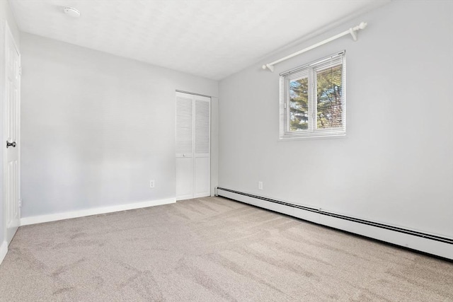 carpeted spare room featuring a baseboard heating unit