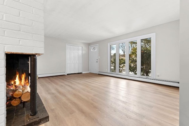 unfurnished living room with a baseboard radiator, a fireplace, and light hardwood / wood-style flooring