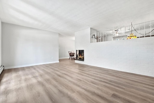 unfurnished living room featuring wood-type flooring and brick wall