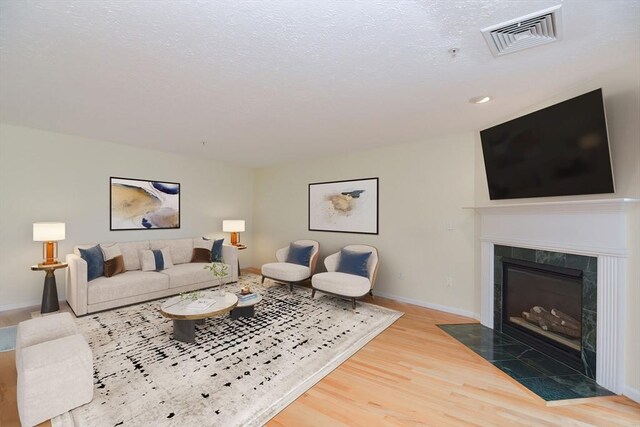 living area featuring visible vents, wood finished floors, a fireplace, baseboards, and recessed lighting