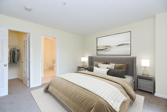 bedroom featuring carpet floors, baseboards, a spacious closet, and ensuite bathroom