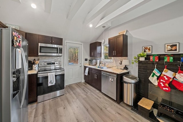 kitchen featuring backsplash, lofted ceiling with beams, hanging light fixtures, and stainless steel appliances