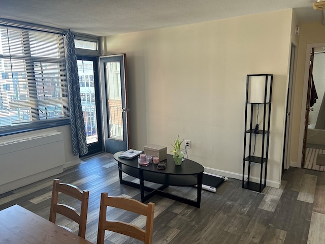 living room featuring radiator heating unit, a textured ceiling, plenty of natural light, and dark wood-type flooring