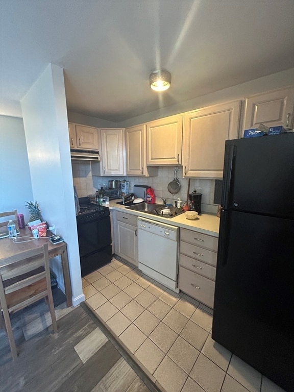 kitchen featuring ventilation hood, light tile patterned floors, backsplash, black appliances, and sink