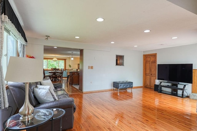 living room with light wood-style floors, recessed lighting, and baseboards