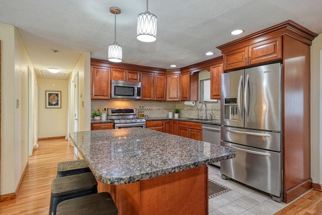 kitchen featuring appliances with stainless steel finishes, a sink, baseboards, a breakfast bar, and tasteful backsplash