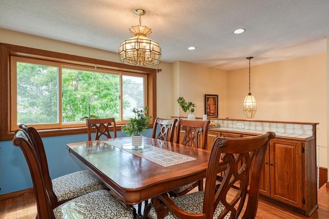 dining space with light wood-type flooring, a textured ceiling, recessed lighting, and baseboards