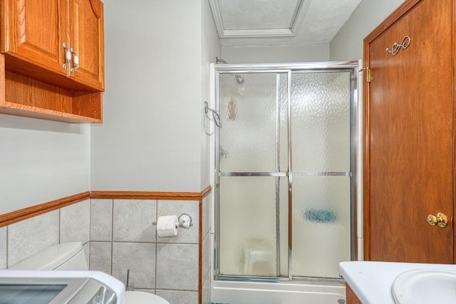 full bath with toilet, tile walls, a shower stall, a wainscoted wall, and vanity