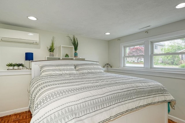 bedroom with a wall mounted AC, baseboards, recessed lighting, and a textured ceiling